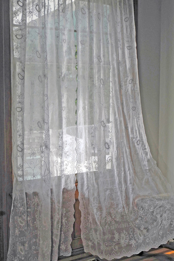 window curtain in white cotton organdy embroidered with sunflower like motif.