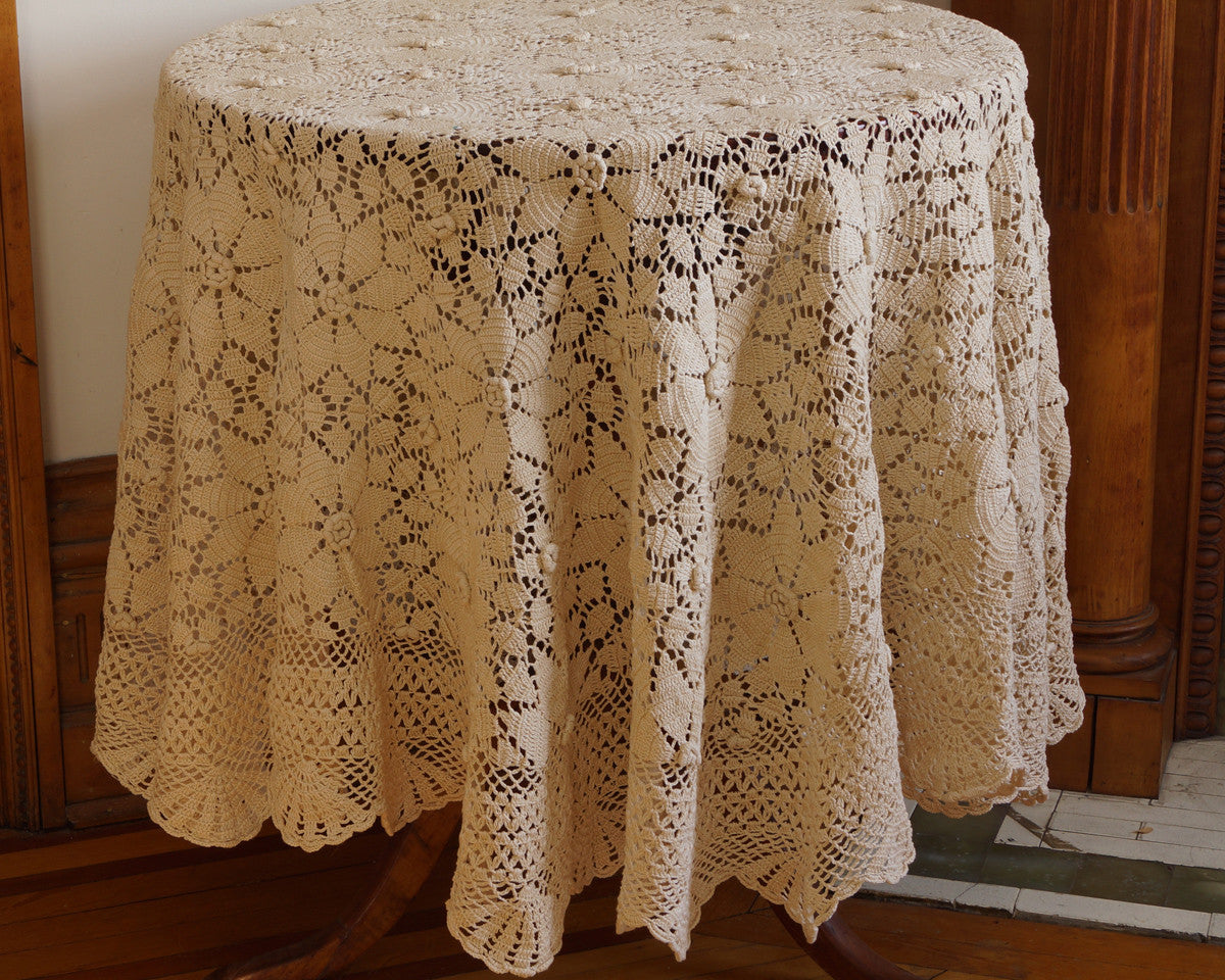 Beautiful hand crochet, 68" round tablecloth in lush cream color, featuring dimensional rosette design and scalloped edge.