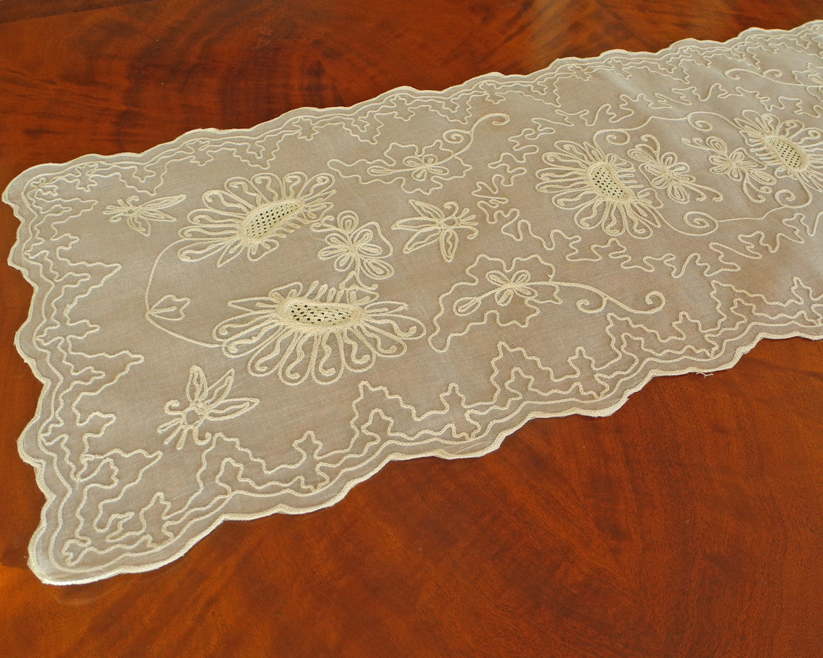 Table runner or dresser scarf embroidered with sunflower like motif and graceful chain stitch along the scalloped edges on 100% cotton organdy.
Color is ecru on ecru.