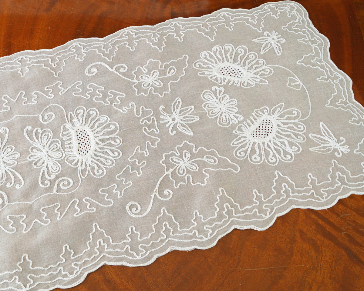 Table runner or dresser scarf embroidered with sunflower like motif and graceful chain stitch along the scalloped edges on 100% cotton organdy. White embroidery on ecru.