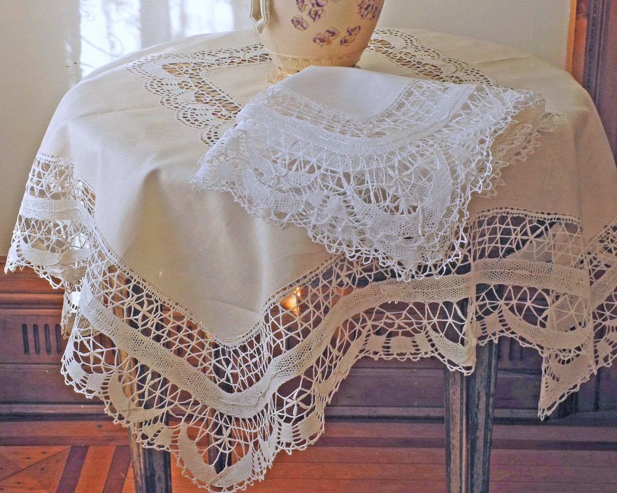 Pure linen tablecloth decorated with hand made cluny lace border and center inset. In white and ecru.